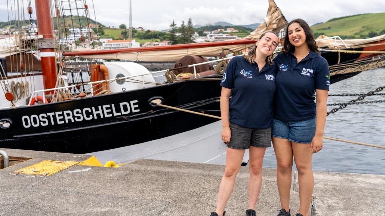 Priya Talreja smiles alongside another participant in front of the tall ship named Oosterschelde in the Azores.