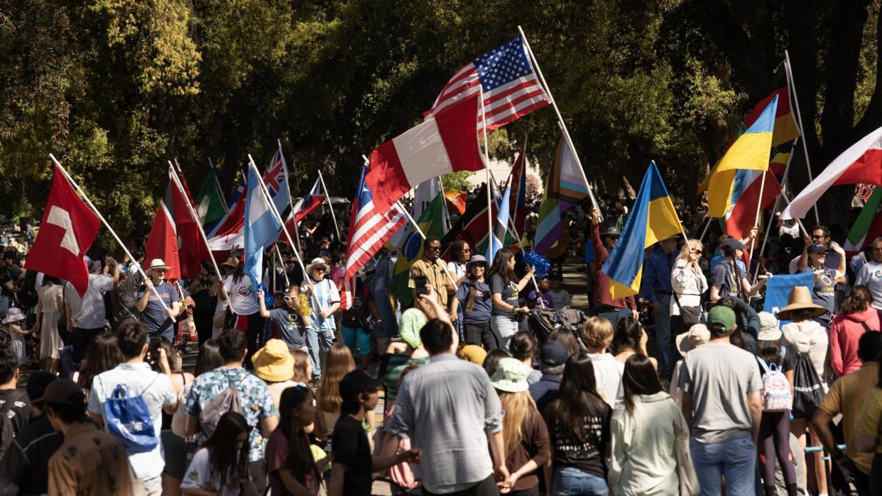 A group of people gathered outside on the UC Davis campus holding up different flags from over 20 countries.