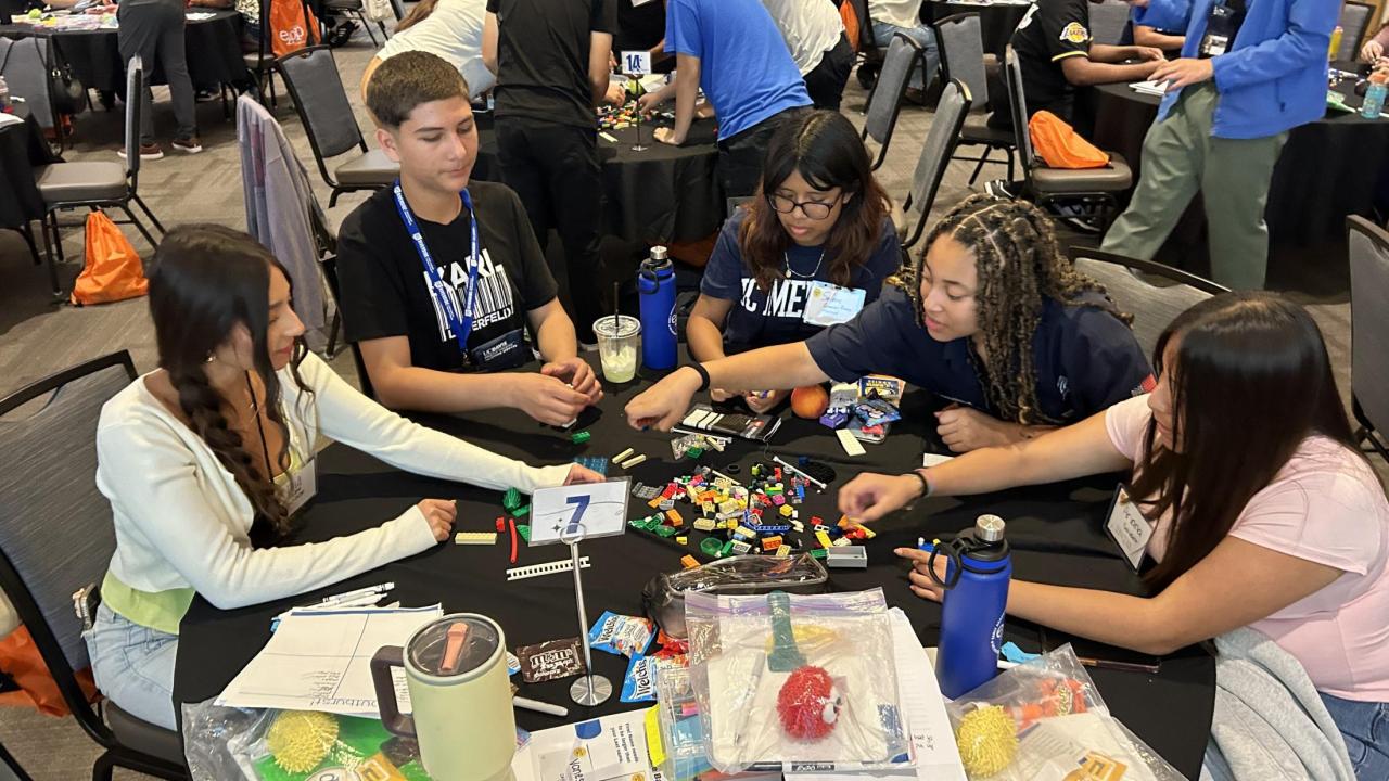 A group of high school students sit around a table and sort colorful Lego bricks during a team activity at the UC Davis ARC Ballroom.